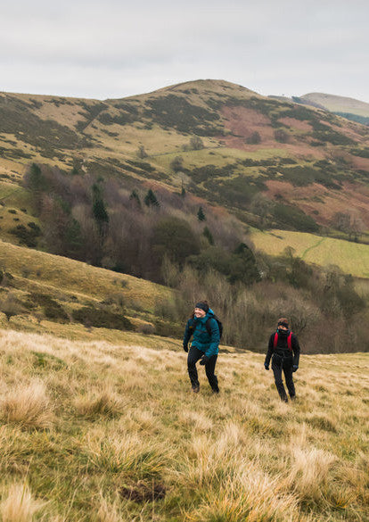 Hikers walking wearing in field Trekmates outdoor accessories. The walkers are wearing Trekmates headwear, Gaiters, Gloves, Packs and Dry liners.