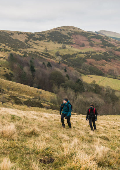 Hikers walking wearing in field Trekmates outdoor accessories. The walkers are wearing Trekmates headwear, Gaiters, Gloves, Packs and Dry liners. 